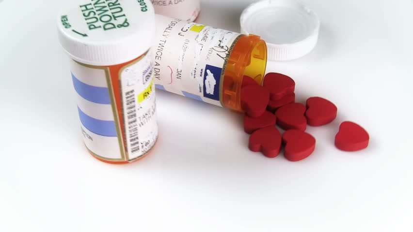 Prescription medicine bottles with tiny red hearts as pills. Rotating around