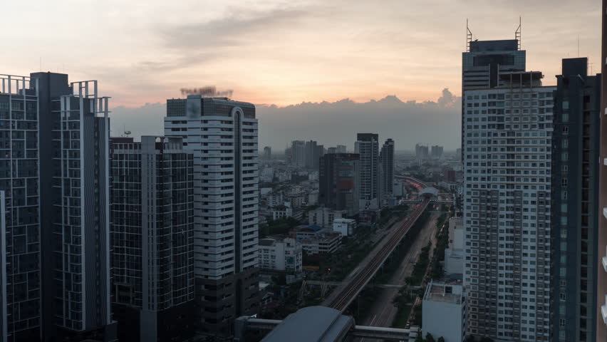 Time lapse shot of cityscape with skyscrapers and buildings on the foreground and industrial smog under city on the background in the evening. Bangkok, Thailand