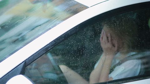 sad girl crying in the car. rain on the street. woman in hysterics