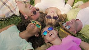 Guys and girls watching funny video on phone while lying on grass, happiness