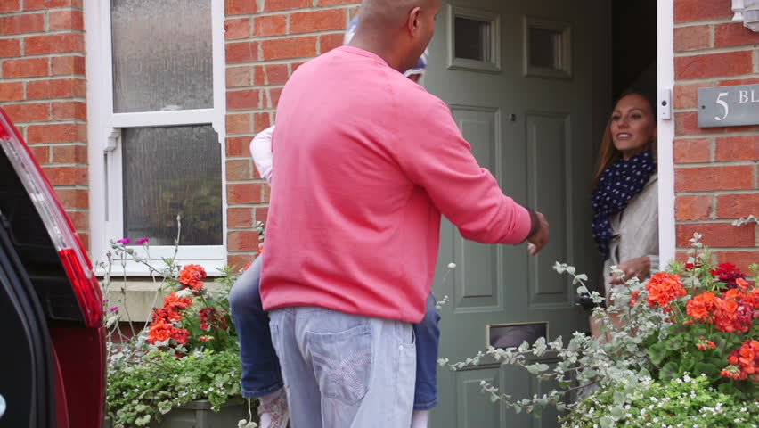 Family of five getting ready to gout in their car. The eldest son and daughter are sitting in the boot looking at a smart phone together.