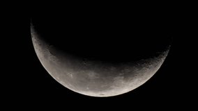 Astronomy video: telescopic view on the moon crescent with all the lunar surface details (marina, mountains, craters) visible. 
