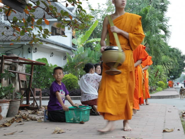LUANG PRABANG, LAOS - OCTOBER 27: Two women give sticky rice to monks during the