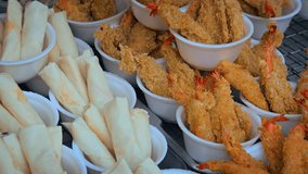 Battered and fried prawns. along with egg rolls. displayed for sale at a public market in Thailand. Video 4k