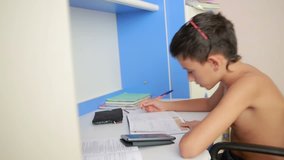 Teenage boy doing homework using a cell phone. natural video