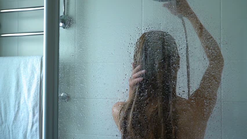 Young slim woman taking a shower and washing her hair. 