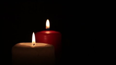 Two candle burning close up on black background