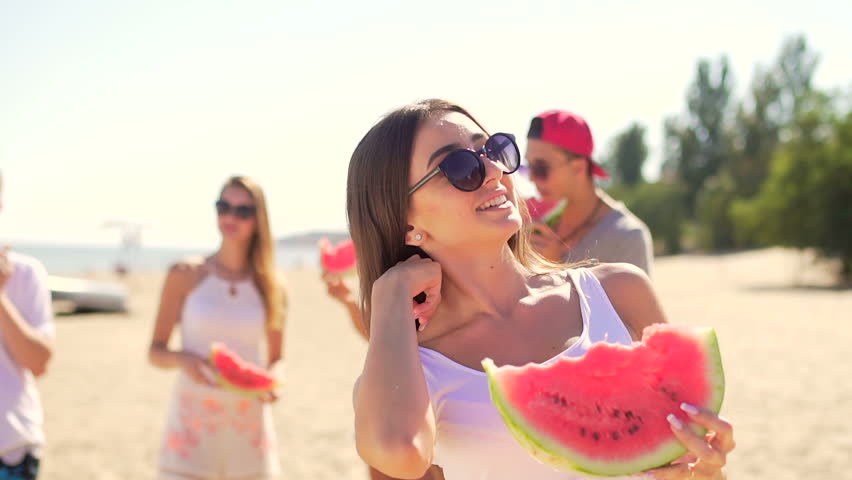 Handsome young woman eating watermelon. Friends at background Royalty-Free Stock Footage #19428901