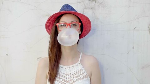 Hipster girl blows big bubble from bubble gum
