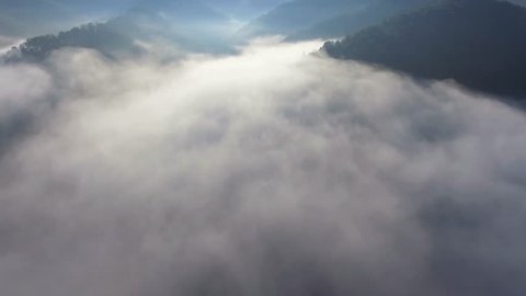 Landscape misty panorama. Fantastic dreamy sunrise on rocky mountains with view into misty valley below. Foggy clouds above forrest. View below to fairy landscape. Foggy forest hills.View from above.