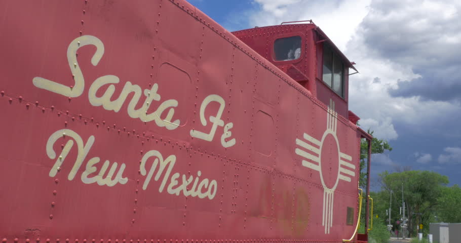 A red train boxcar with a sign reads Santa Fe, New Mexico. The welcome billboard establishes the famous tourist location in the southwestern United States. 