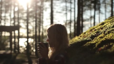 Silhouette of a Girl With a Mug of Tea in the Sunset at the House With a Roof of Moss