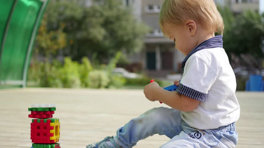 boy build plastic block on wooden table in park