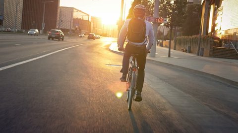 Commuter riding a bike on his morning travel to job. Smartly dressed active young man traveling to job in the city early in the morning. Sunrise in front of the cyclist.