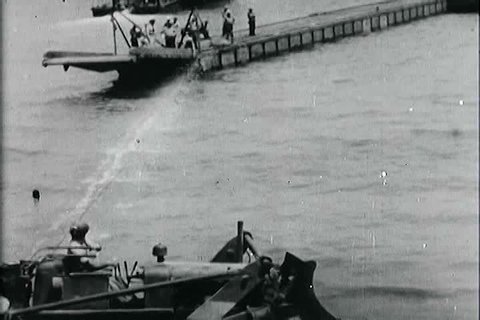 Landing ship tanks and portable docks are attacked on the coast of the Sicily beach head as Navy Seabees look on during World War II in the 1940s. (1940s)