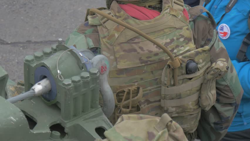 Nato Soldiers Are Talking to Young Civilian People at Parade on a City Square. People Are Standing at Military Vehicles. Soldiers in Camouflage. Woman in Blue Jacket. People Are Watching the Parade,