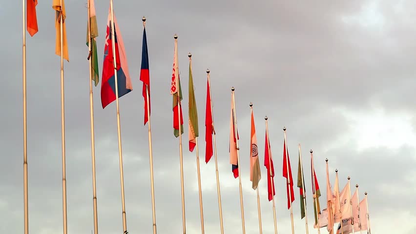 Many Flags of Countries and Corporations Are Fluttering in the Wind Against a Blue Cloudy Sky