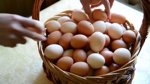 Woman adds eggs in wicker basket