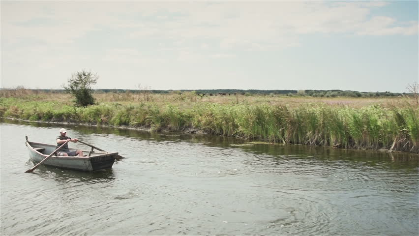 The guy in the boat floating on the narrow river. Slow motion