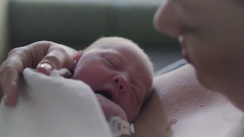 Close Up of Newborn Baby Dreaming on Mothers Chest in Hospital Delivery Room