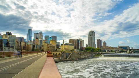 Minneapolis Skyline Stone Arch Bridge Time Lapse Logos Removed 1080p 4k - Stone arch bridge in Minneapolis time lapse with water and buildings. Skyline view with people minnesota
