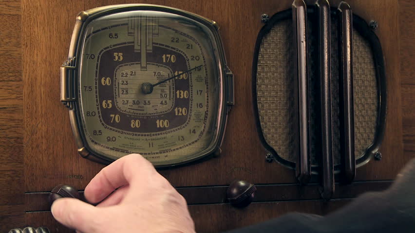 Male hand turning on and tuning a antique radio