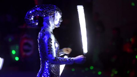 MOSCOW, RUSSIA - JANUARY 30, 2016: Final of Moscow stage of National Cup of "Robot wars-2016" at VDNH. Close view of woman performing on arena in darkness in strange alien costume and with lightsabers