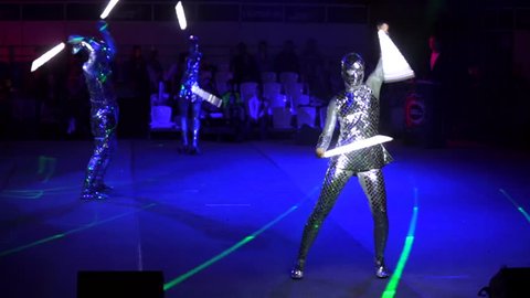 MOSCOW, RUSSIA - JANUARY 30, 2016: Final of Moscow stage of National Cup of "Robot wars-2016" at VDNH. A few people perform on arena in darkness in strange alien costumes and with lightsabers