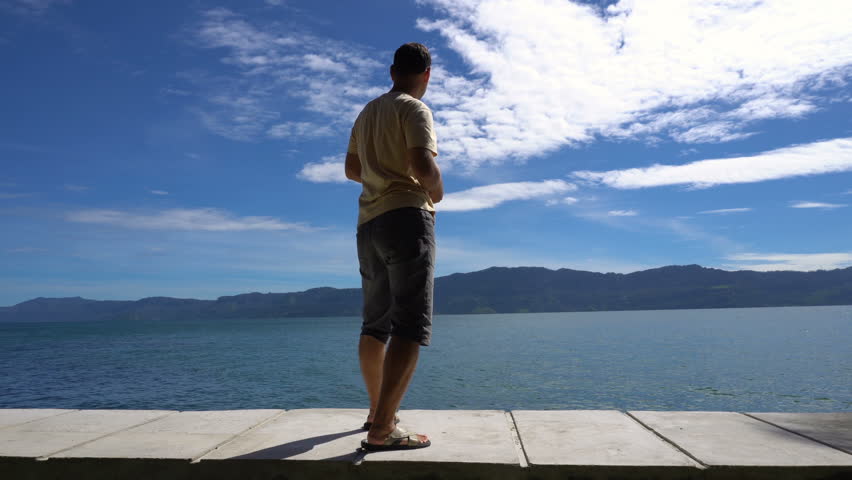 Young man plays ducks and drakes on Toba lake, Sumatra, Indonesia