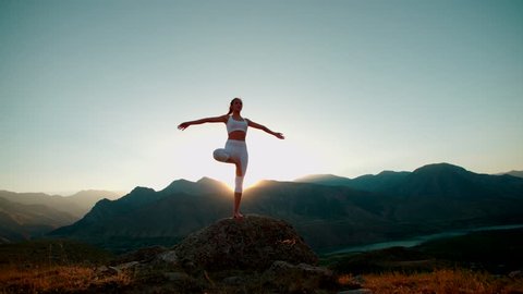 4K yoga in the mountains,a beautiful girl dressed in white ,sun,sun flare, slow motion