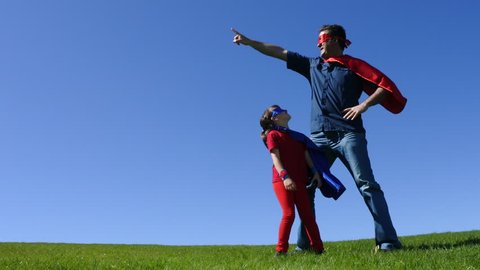 Superhero father shows his daughter (age 7-8) how to be a superhero outdoors. Concept photo of Superman, Super hero,superhero, childhood, supportive,  fatherhood and parenthood. Real people. Copy spac