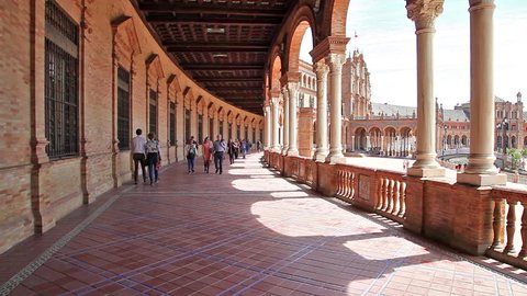 Seville, Andalusia, Spain - April 18, 2016: The famous Square of Spain, from the gallery with columns, example of mixing Regionalism Architecture Renaissance and Moorish styles. with walking tourists.