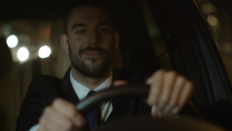 Happy Smiling Businessman Driving a Car through Streets of Night City. Shot on RED Cinema Camera in 4K (UHD).