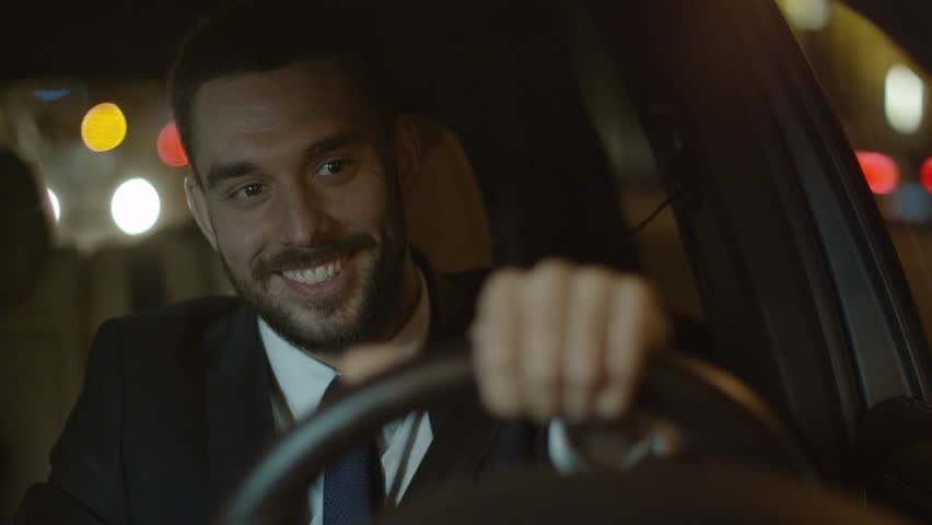 Happy Smiling Businessman Performing Winning Gesture while Driving a Car at Evening. Shot on RED Cinema Camera in 4K (UHD). Royalty-Free Stock Footage #19484302