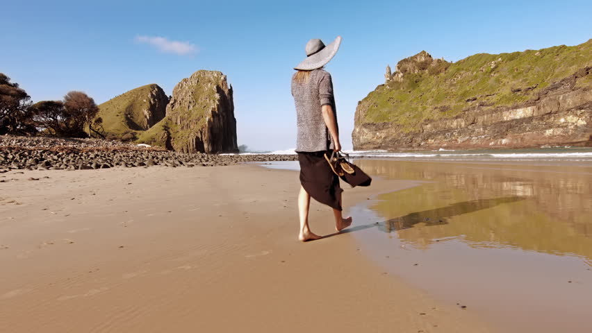 4k Wide of Happy independent fashion woman with hat,  walking and having a stroll on the beach. 