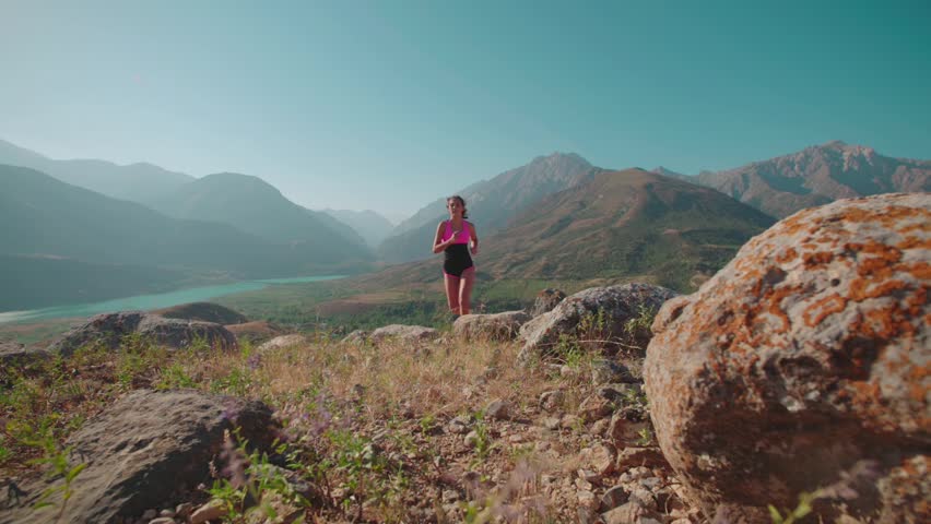 fitness in the mountains, a beautiful girl in sports clothes, training,running in mountainous terrain, slow motion