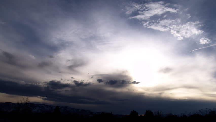 Time lapse of clouds including mountain range and trees.