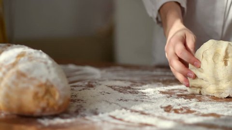 Female hands kneading dough in flour on table, dolly shot 