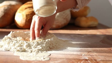 Baker adding milk to flour on table, dolly shot  : vidéo de stock
