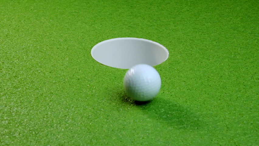 A golf ball rolls into the cup, multiple shots