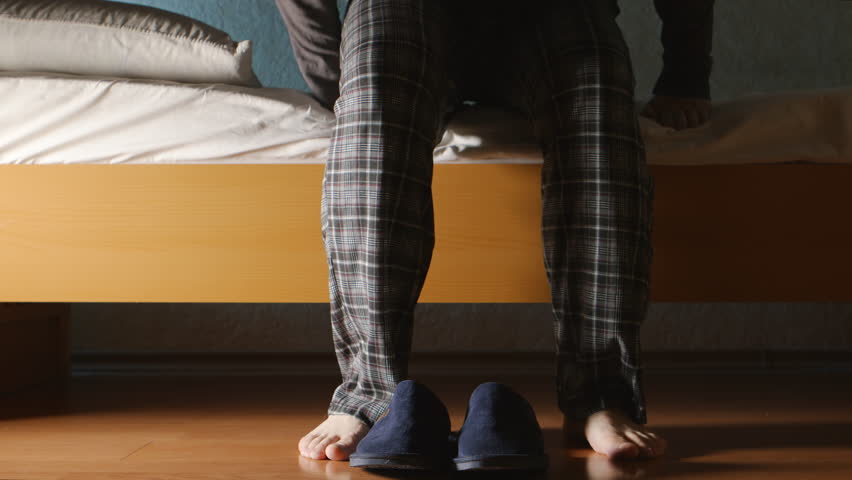 Man gets up from a bed in the night then wears a slippers and goes Royalty-Free Stock Footage #19516711