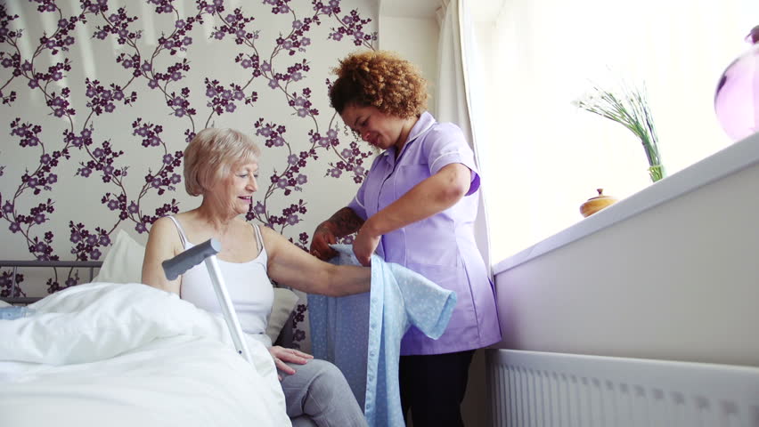 Home caregiver helping a senior woman get dressed in the bedroom of her home.  Royalty-Free Stock Footage #19528828