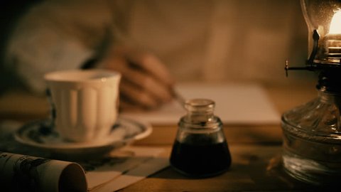 A man writing with a dip ink pen lit by the light from an oil lamp.