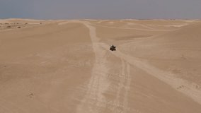 Aerial shooting from flying drone of woman wanderer is riding on quad bike on a sandy beach in sunny day during her unforgettable summer vacation to tropical Asia. Video with high quality resolution 