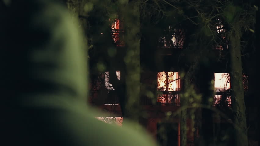 Hooded stalker stalking apartment from a distance at night,rack focus.A hooded ominous figure stalking a residential building at night Royalty-Free Stock Footage #19537486