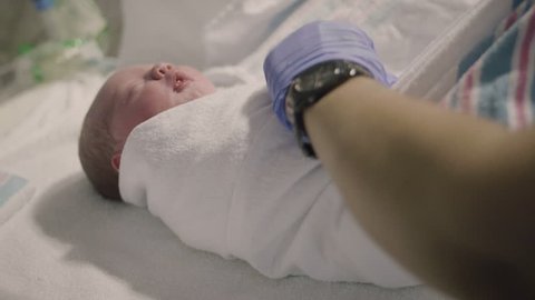 Nurse Swaddling Newborn Baby in Hospital Delivery Room