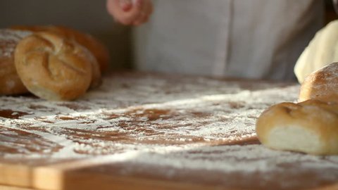 Baker hand throwing flour on the table and kneading dough, slow motion
