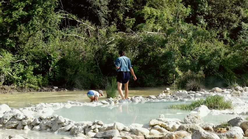 Woman with her son enjoying their time next to the pond, steadycam shot
