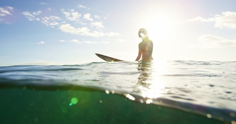 Beautiful surfer girl enjoying sunset surf