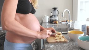 Pregnant woman cutting banana in the kitchen